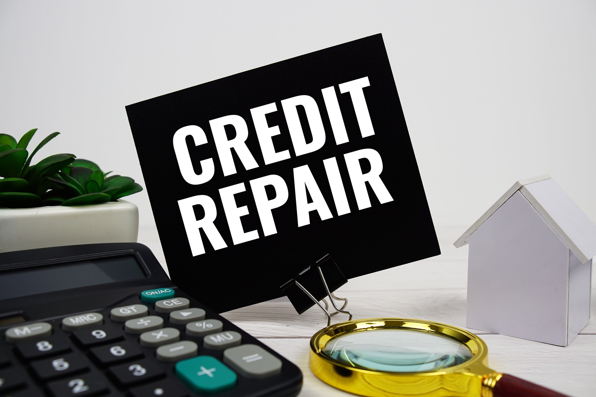 Credit Repair text message with house model, calculator and magnifying glass on wooden background